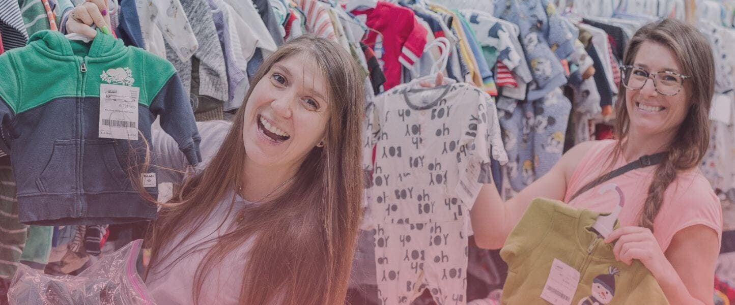 Two moms shopping for clothes holding up a jacket and pajamas