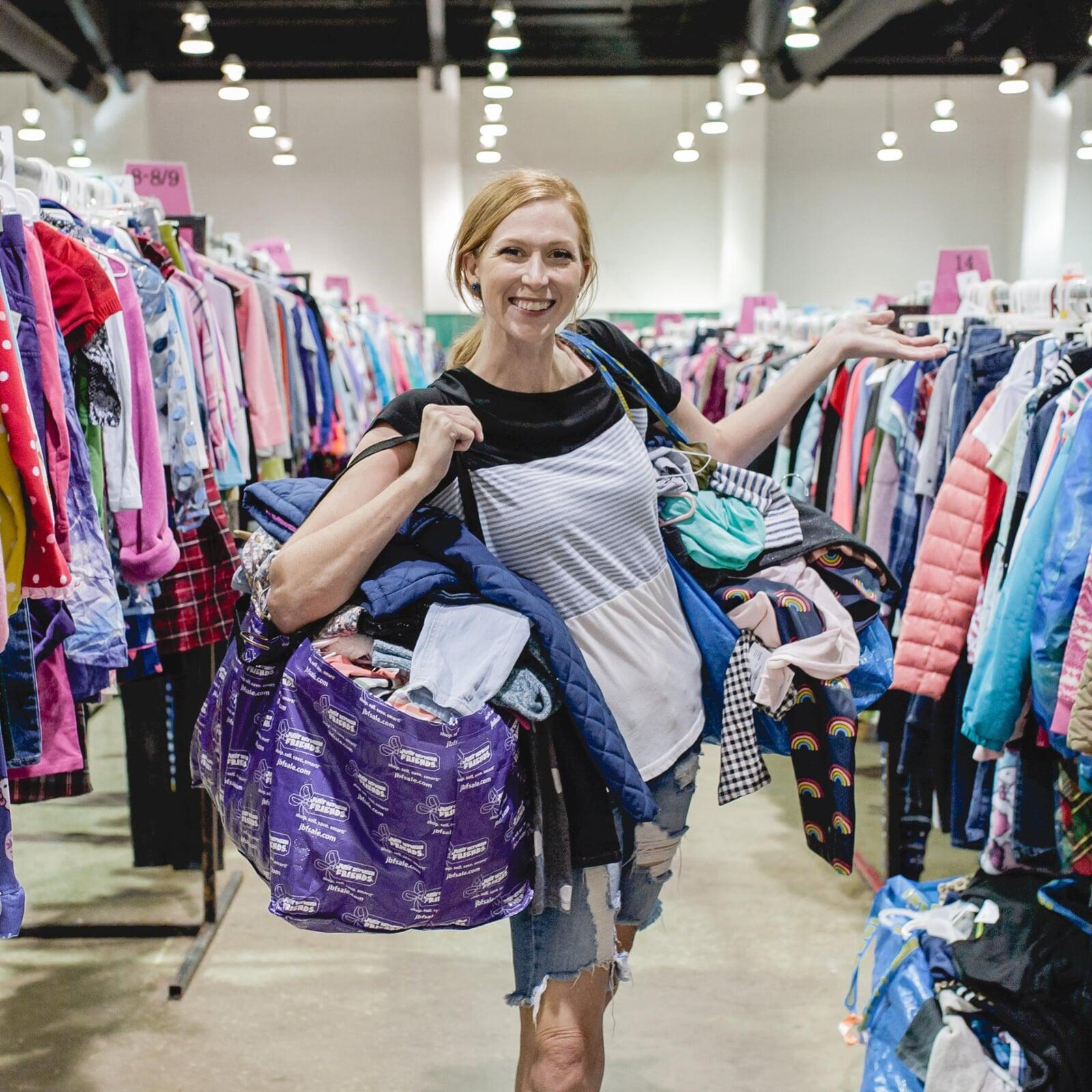 Mom holds hand up to show rows and rows of clothing for sale at 50 to 90% off retail prices!