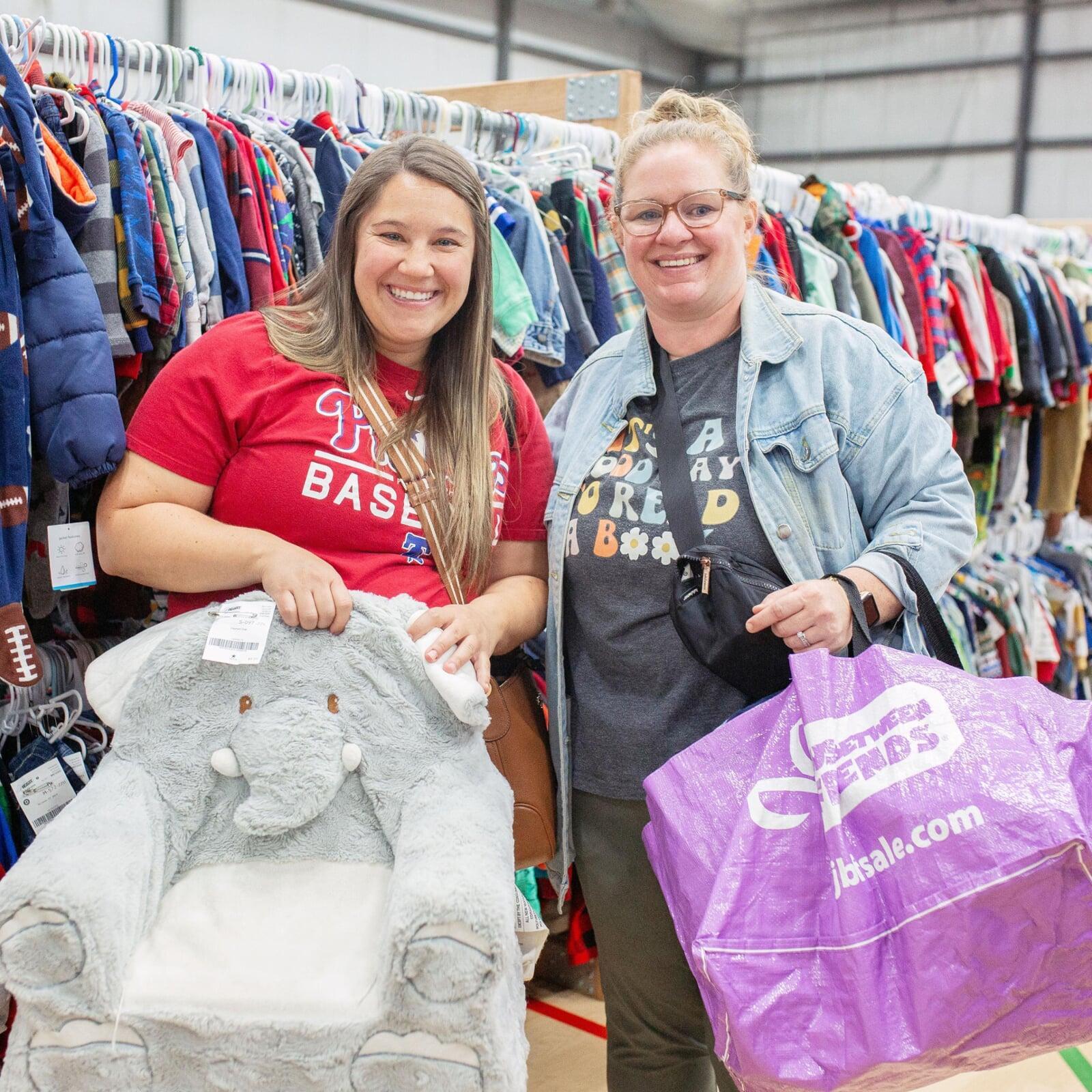 Two moms holding a chair and shopping bag